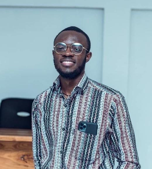 Smiling young Black man wearing glasses and earbuds, patterned shirt